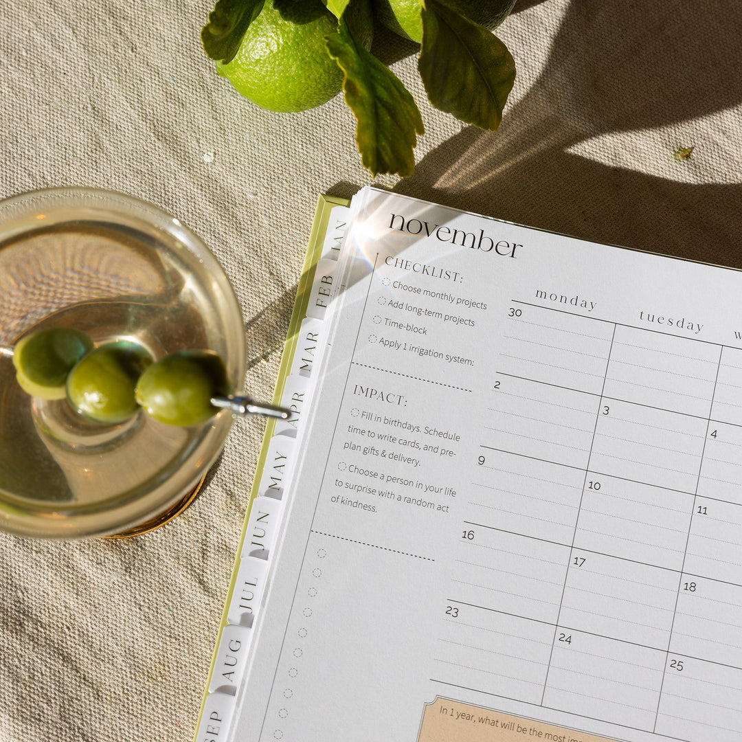 Calendar open to November with a glass of cocktail and limes on a textured surface