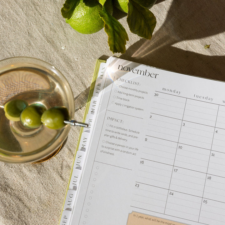 Calendar open to November with a glass of cocktail and limes on a textured surface